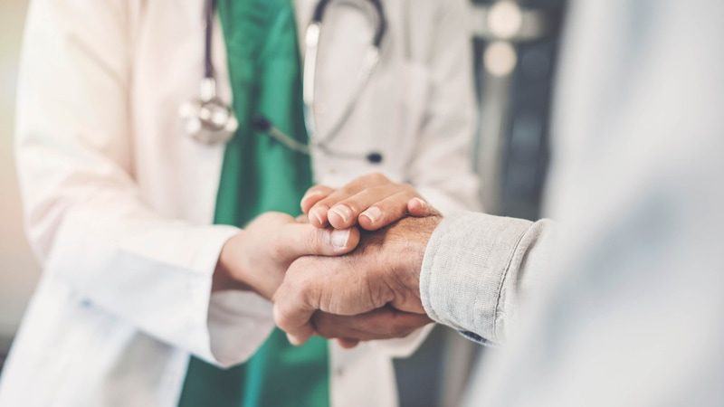 A doctor holding hands of a patient